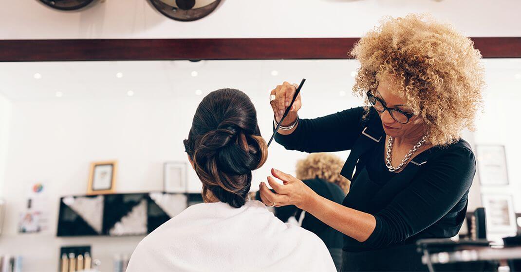 hairdresser creating up do style on client