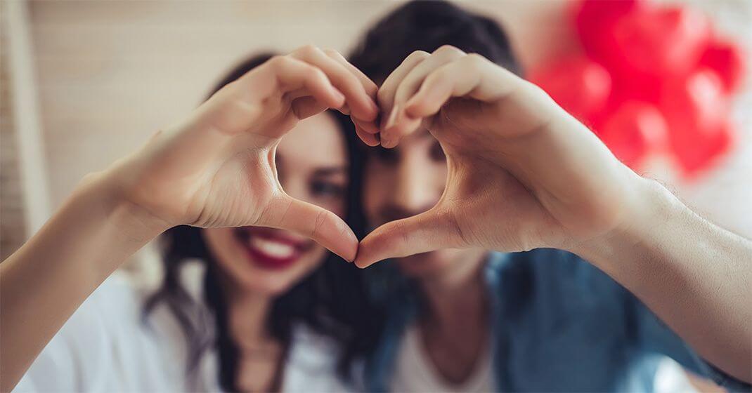 two people making a love heart with hands