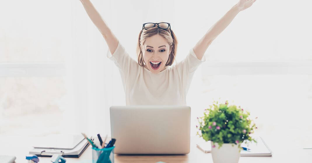 excited woman sitting at laptop