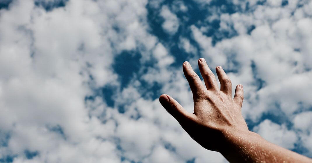 man reaching towards sky