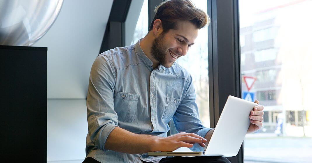 man sitting in salon using laptop