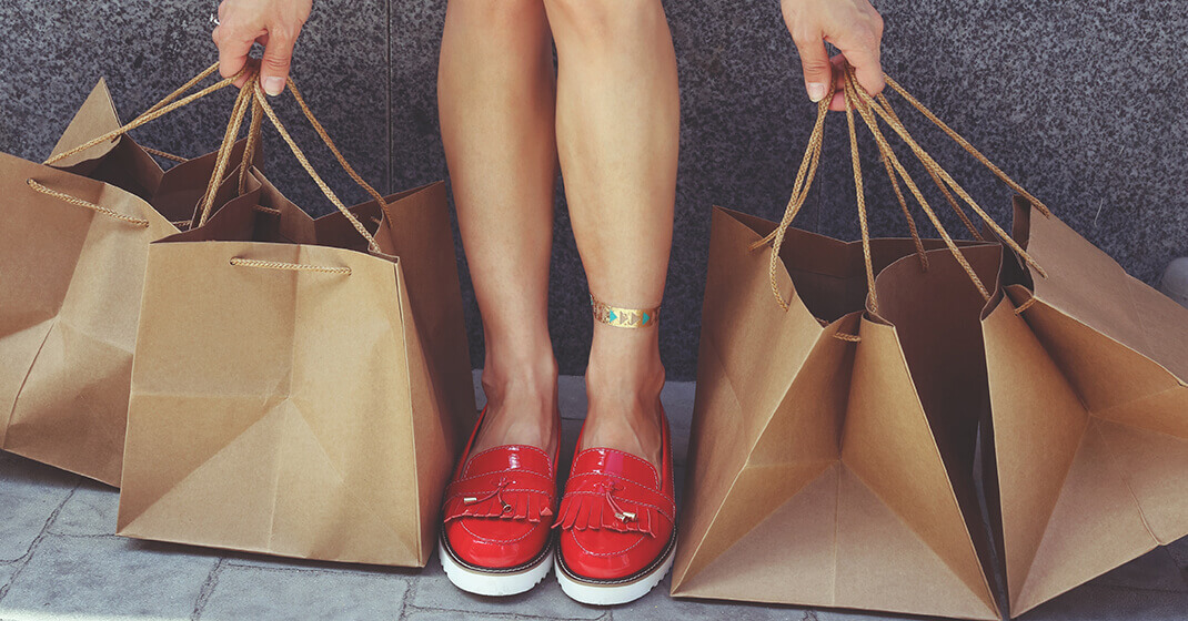 woman picking up shopping bags wearing cute red shoes
