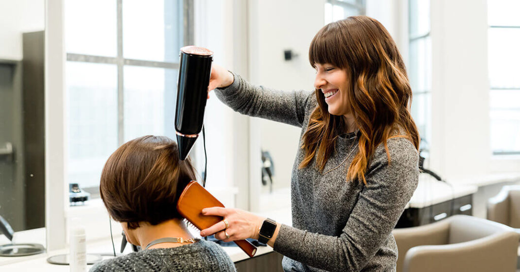 Hairdresser styling clients hair to reach her salon targets